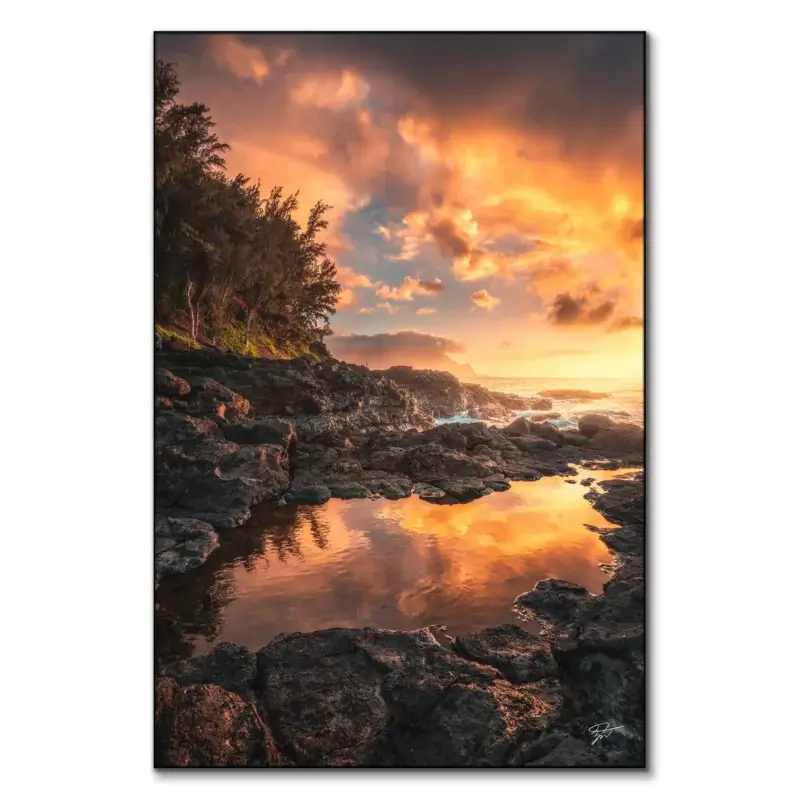 Sunset over the rugged coastline of Kauai, Hawaii, with fiery sky colors, volcanic rocks, and a tranquil tidal pool.