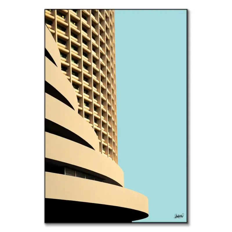 Tan curved high-rise building with repetitive windows against a light blue sky.