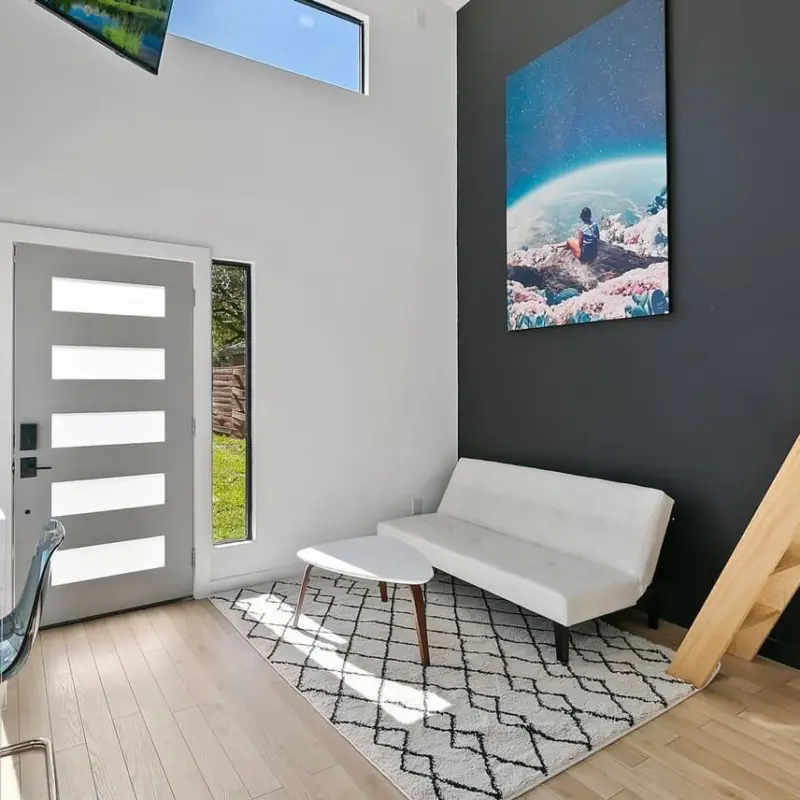 Massive surreal wall art of person looking out over another planet hangs on dark gray wall in open entryway
