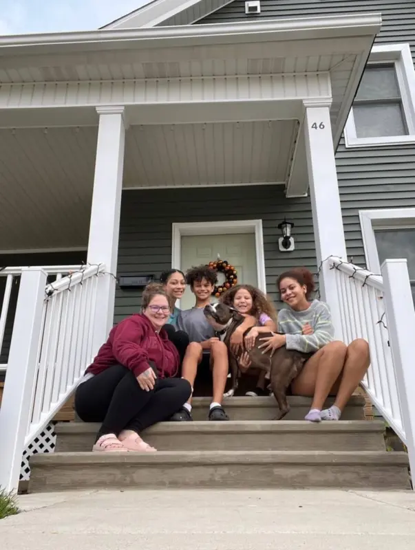 Single mother of 4 sits on the front steps of home with her children.