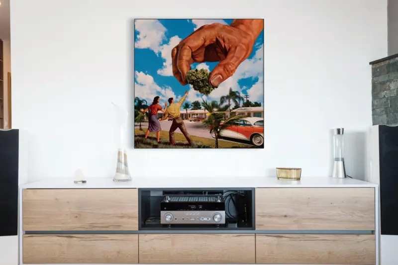 Large weed art featuring hand of God reaching down delivering a nug to a man and woman in a suburban Florida neighborhood in the 1950s hangs above wooden entertainment center in a stoner's living room.