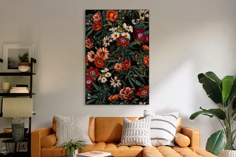 Black, red, and green floral marijuana patterned print hangs on neutral wall in living room above modern orange couch.